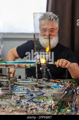 Glassworker while shaping the glass with a very high temperature flame Stock Photo