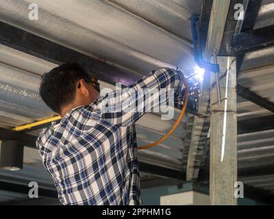 A welder is working on a steel frame. At the construction site. Stock Photo