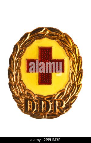 Potsdam, Germany - DEC 12, 2022. Badges, orders and medals from GDR (DDR). Close-up of a National Defence Badge of the German Red Cross in bronze. Clipping path. Macro isolated on white. Stock Photo