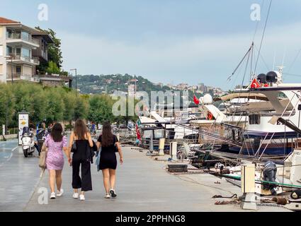 Pedestrians walking by the Bosphorus between Bebek and Hisari districts, and docked boats and yachts, Istanbul, Turkey Stock Photo