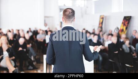 Speaker at Business Conference with Public Presentations. Audience at the conference hall. Entrepreneurship club. Rear view. Horisontal composition. Background blur Stock Photo