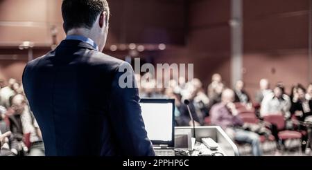 Speaker giving a talk on corporate business conference. Unrecognizable people in audience at conference hall. Business and Entrepreneurship event Stock Photo