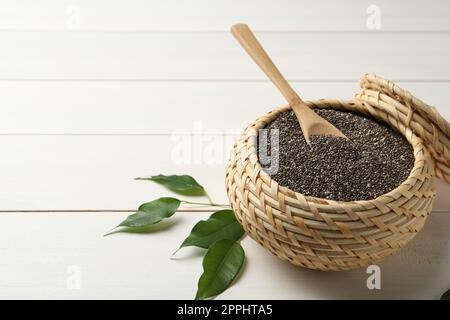 Wicker box with chia seeds and spoon on white wooden table. Space for text Stock Photo