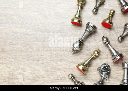Silver and golden chess pieces on wooden table, flat lay. Space for text Stock Photo