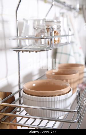 Many different ramekins on metal rack in kitchen Stock Photo