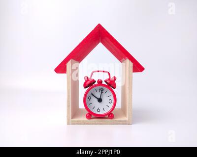 Alarm clock and toy house on a white background. Stock Photo