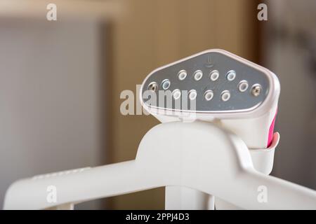 Close up of electric hand steam generator while it's hot on the ironing board place for clothes Stock Photo