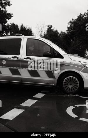 Vertical grayscale of two officers in a German police car on a rainy day in Dusseldorf Stock Photo