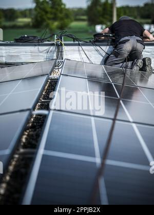 Male team engineers installing stand-alone solar photovoltaic panel system. Electricians mounting blue solar module on roof of modern house. Alternative energy concept Stock Photo
