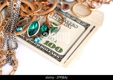 Many expensive golden and silver jewerly rings, earrings and necklaces with big amount of US dollar bills on white background. Pawnshop or jewerly shop Stock Photo