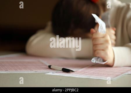 A sad young girl suffers from a loss after looking the unlucky result of the lottery gambling. The concept of losing the lottery and spend money Stock Photo
