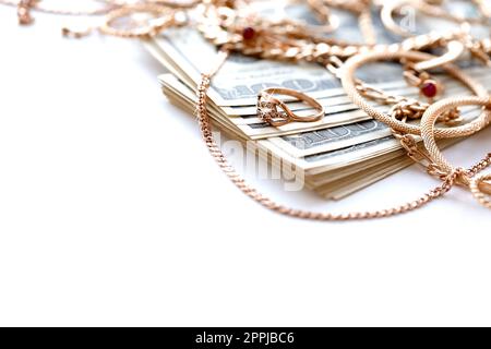 Many expensive golden jewerly rings, earrings and necklaces with big amount of US dollar bills on white background. Pawnshop or jewerly shop Stock Photo