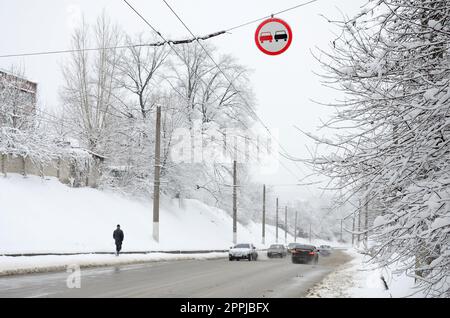 Overtaking is prohibited. The sign prohibits overtaking all vehicles on the road section. A road sign hanging over a snow-covered road Stock Photo