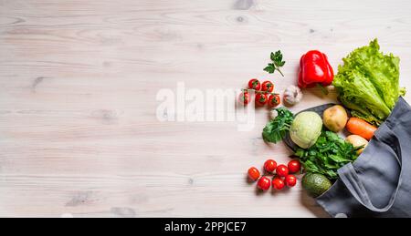 Healthy food. Organic vegetables, vegan vegetarian raw food ingredients in textile bag on wooden background, copy space. Delivery or grocery supermark Stock Photo