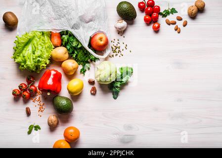 Fruits and vegetables in white plastic bag. Organic fruits, vegetables, vegan vegetarian raw food ingredients  on wooden background, copy space. Deliv Stock Photo