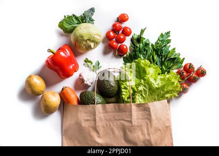 Healthy food in paper bag. Organic vegetables, vegan vegetarian food ingredients in paper bag isolated on white background. Delivery or grocery superm Stock Photo