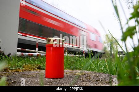 24 April 2023, Lower Saxony, Neustadt am Rübenberge: A candle stands at the railroad crossing where a car was hit by a train on Sunday morning. After the fatal accident in the Hanover region, the police are doing everything they can to clarify the cause. In the accident, three young people had died early Sunday morning (23.04.2023) when their car was hit by a regional train on the level crossing. According to police, they had driven onto the level crossing despite the fact that the half-barriers were closed. Photo: Julian Stratenschulte/dpa Stock Photo