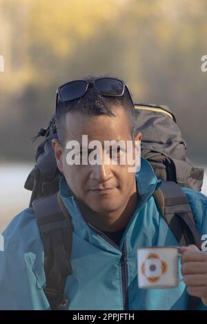 Portrait of traveler man at lake in autumn with a cup of coffee Stock Photo
