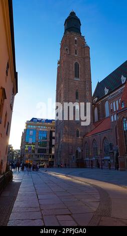 The St Elizabeth Church is hidden behind the houses of old Odrzanska street located next to the Market Square on August 18 in Wroclaw. Stock Photo