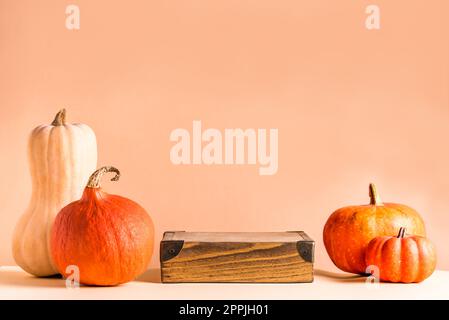 Pumpkins and wooden podium on beige background, copy space. Seasonal trendy product showcase. Halloween or Thanksgiving celebration concept. Stock Photo