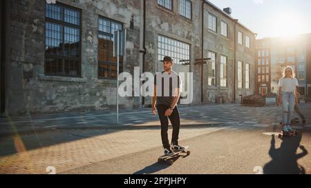 Group of Girls and Boys on Skateboards Through Fashionable Hipster District. Beautiful Young People Skateboarding Through Modern Stylish City Street D Stock Photo