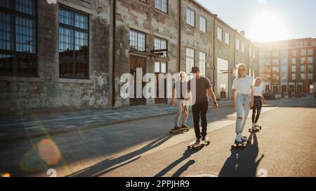 Group of Girls and Boys on Skateboards Through Fashionable Hipster District. Beautiful Young People Skateboarding Through Modern Stylish City Street D Stock Photo