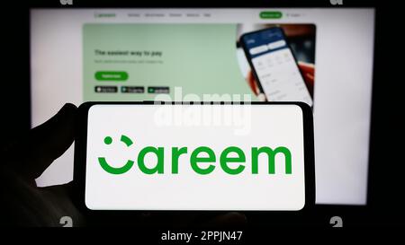 Person holding smartphone with logo of Emirati company Careem Networks FZ-LLC on screen in front of website. Focus on phone display. Stock Photo