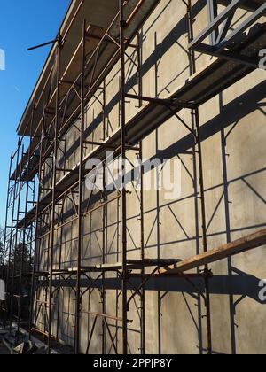 Scaffolding on a new one-story house. Facade works. Building bussiness. Low-rise private building. Plastering the wall of a building. Shop building. Metal production structures. Stock Photo