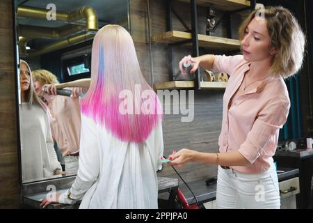 Beautiful blond girl with colored pink hair in a hairdressing salon. Stock Photo