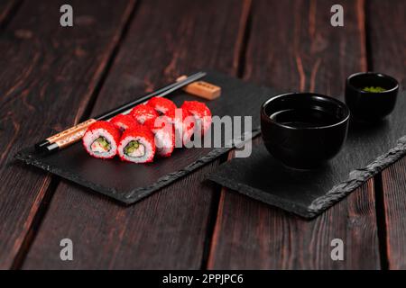 Sushi roll with shrimp and cucumber and tobiko caviar served on black board close-up - Japanese food Stock Photo