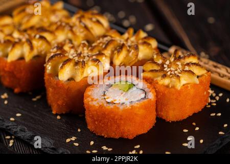 California sushi roll with crab, avocado and tobiko caviar served on black board close-up - Japanese food Stock Photo
