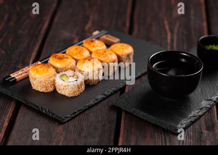 Sushi roll with eel, avocado and cream cheese served on black board close-up - Japanese food Stock Photo
