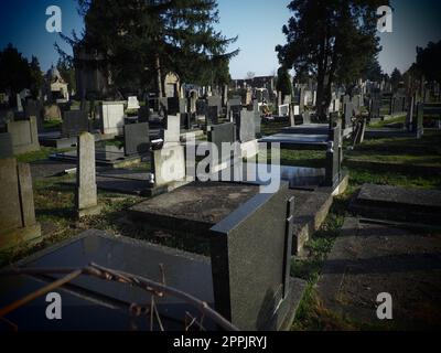 Sremska Mitrovica, Serbia, February 25, 2021. Christian city modern cemetery. Graves with stone monuments and crosses. Granite headstones. Crypt or chapel. Funeral or Halloween theme Stock Photo