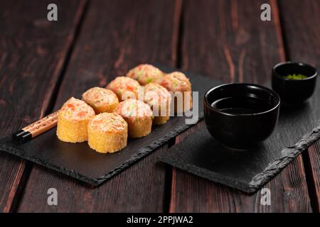 Sushi roll with mayonnaise sauce served on black board and soy sauce. Stock Photo
