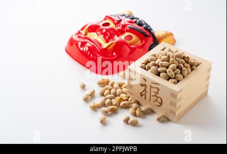 Beans for bean-throwing and masks of ogres placed on a white background. Stock Photo