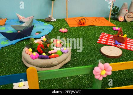 Easter composition made by children at school in the labor lesson. Village yard, eggs in a basket, green artificial grass. Painted fence. Application and sculpture in children's creativity. Stock Photo