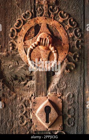 Old, Antique, Vintage and Retro rusty door lock with handle mounted on weathered wooden door Stock Photo