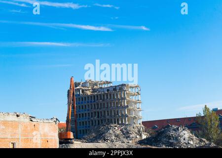 Demolition of the old building with sloopkraan against blue clouds sky. Stock Photo