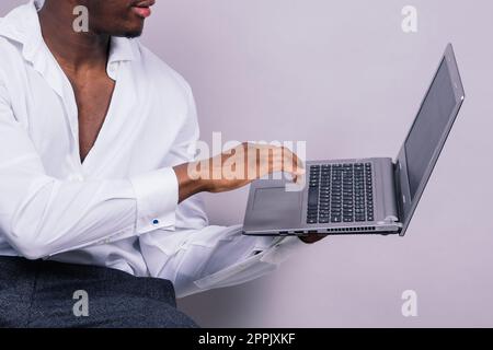 Optimistic african-american male student in casual shirt using laptop pc isolated Stock Photo