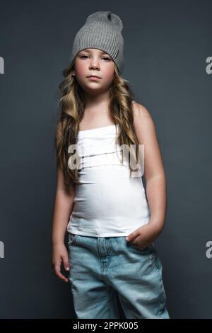 Little girl model professionally posing in the studio in jeans and a white T-shirt. Model tests Stock Photo