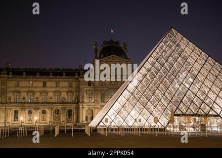 The famous Louvre Palace and its iconic glass pyramide at night, Paris Stock Photo