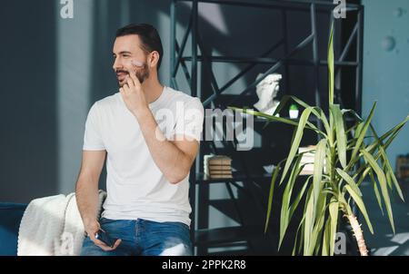 Bearded man using jade face roller for beauty facial massage therapy at home. Beauty treatment. Facial treatment, cosmetology. Facial skincare. Stock Photo