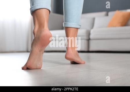 Young woman in sports leggings walks barefoot on the warm floor in