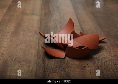 Broken terracotta flower pot on wooden background Stock Photo