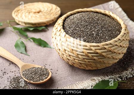 Wicker box and wooden spoon with chia seeds on table Stock Photo