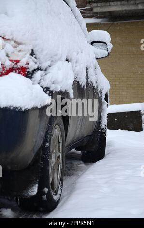 Fragment of the car under a layer of snow after a heavy snowfall. The body of the car is covered with white snow Stock Photo