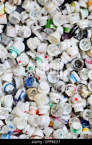 A large number of caps from cans of aerosol paint for graffiti. Smeared with colored paint nozzles lie in a huge pile Stock Photo