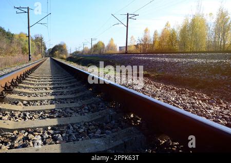 Autumn industrial landscape. Railway receding into the distance among green and yellow autumn trees Stock Photo