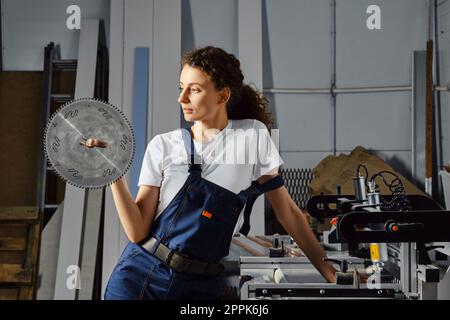 Craftswoman holds a circular saw blade in hand Stock Photo