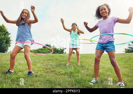 Whipped up in a hula frenzy. a group of young girls playing with hula hoops in the park. Stock Photo